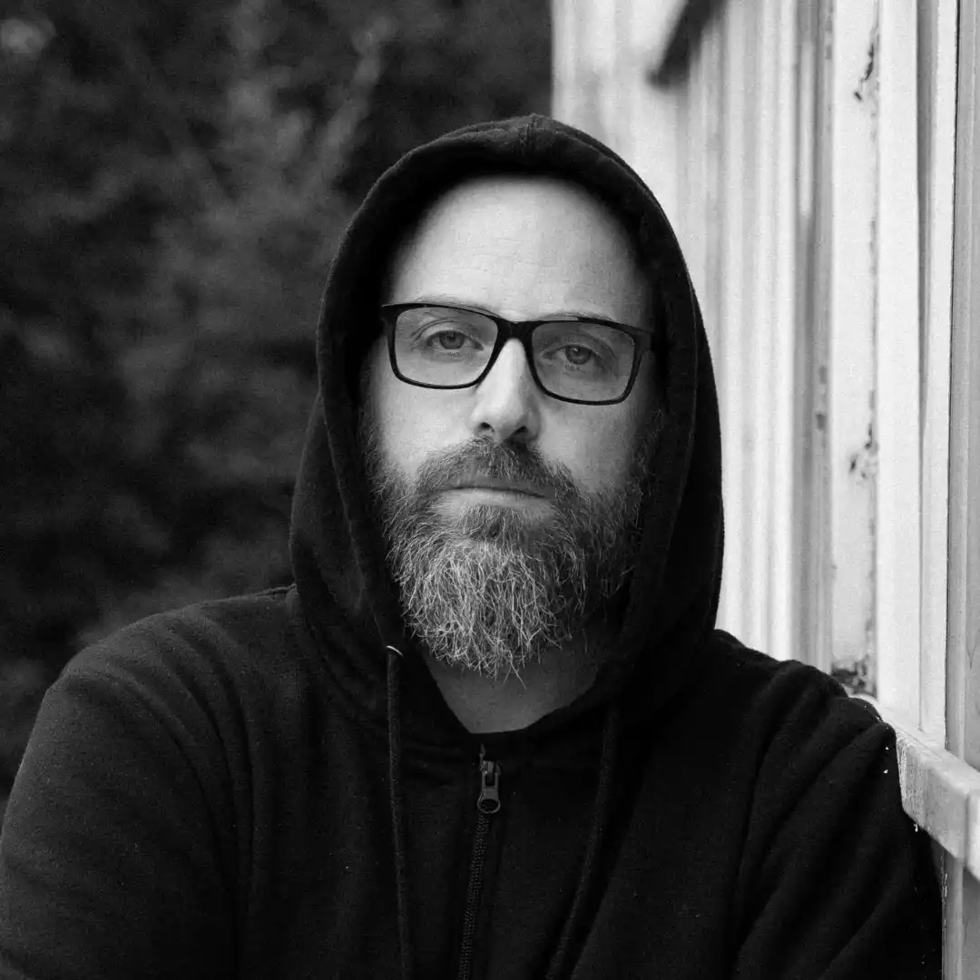 Man in a dark hoodie and glasses.